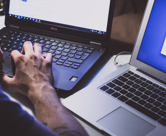 hands on two laptops